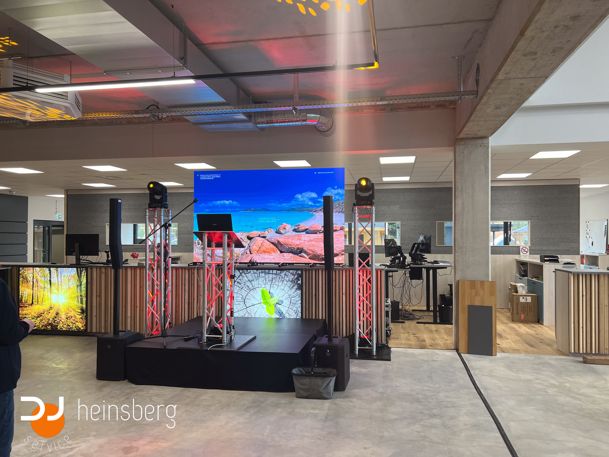 Bühnenpodest mit Laptop und Lichttechnik und einem LED-Videoscreen im Hintergrund.