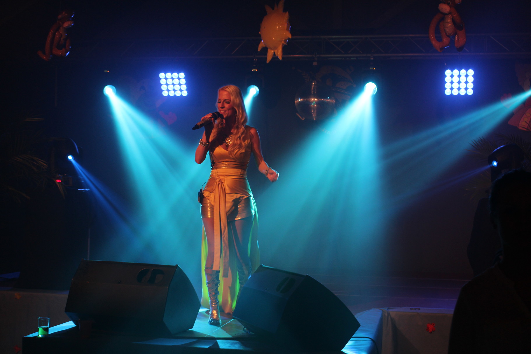 Sängerin auf einer blau-türkis beleuchteten Bühne mit Lichttechnik.