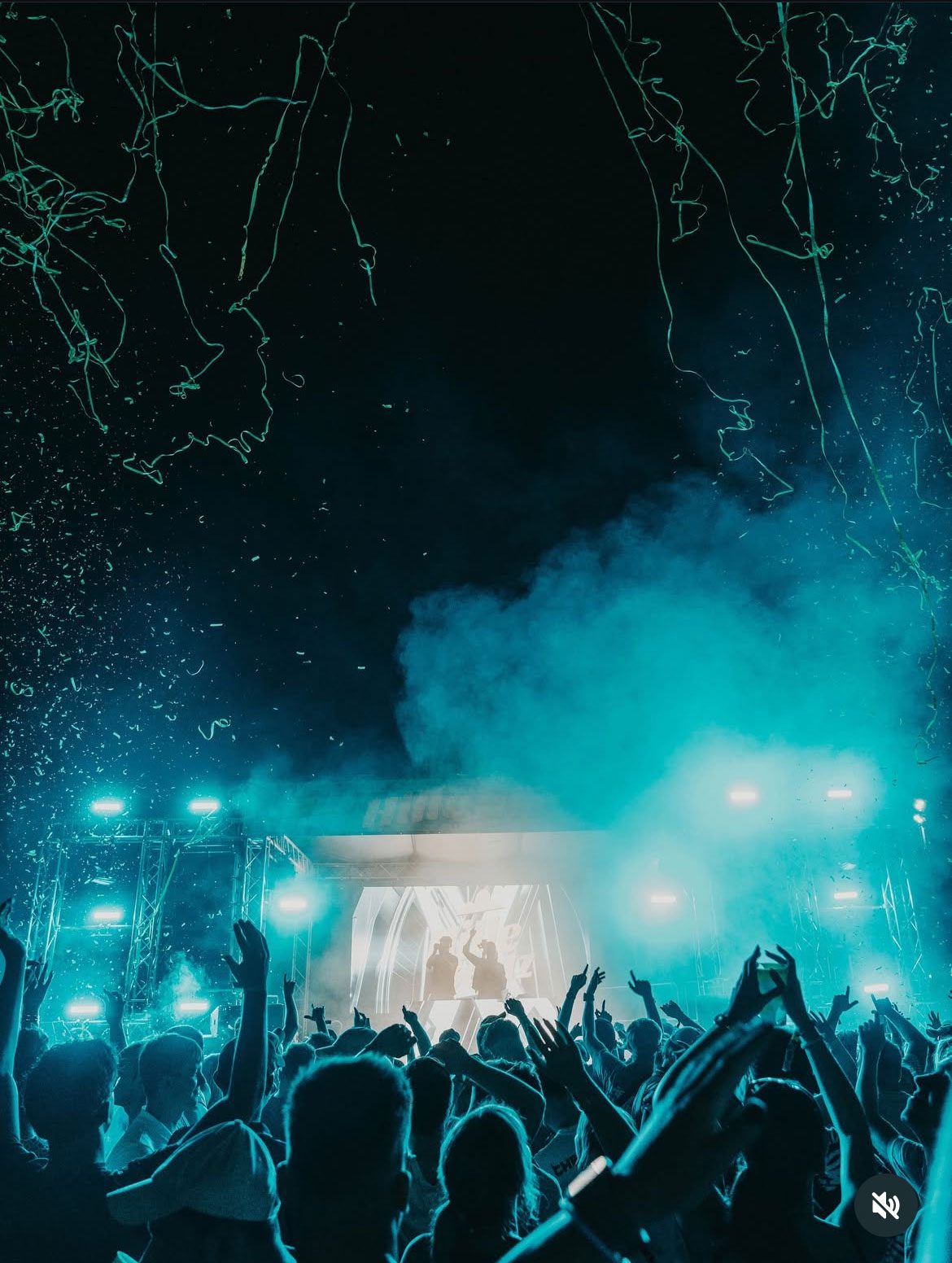 Emotionsbild einer blau leuchtenden Bühne, klatschende Menschen und Konfetti im Vordergrund.