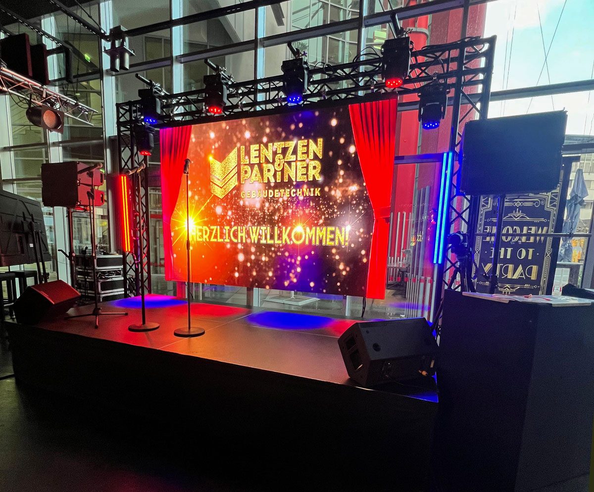 LED-Wand auf einer Bühne mit Moving Heads und LED-Bars, sowie portablen Lautsprechern.