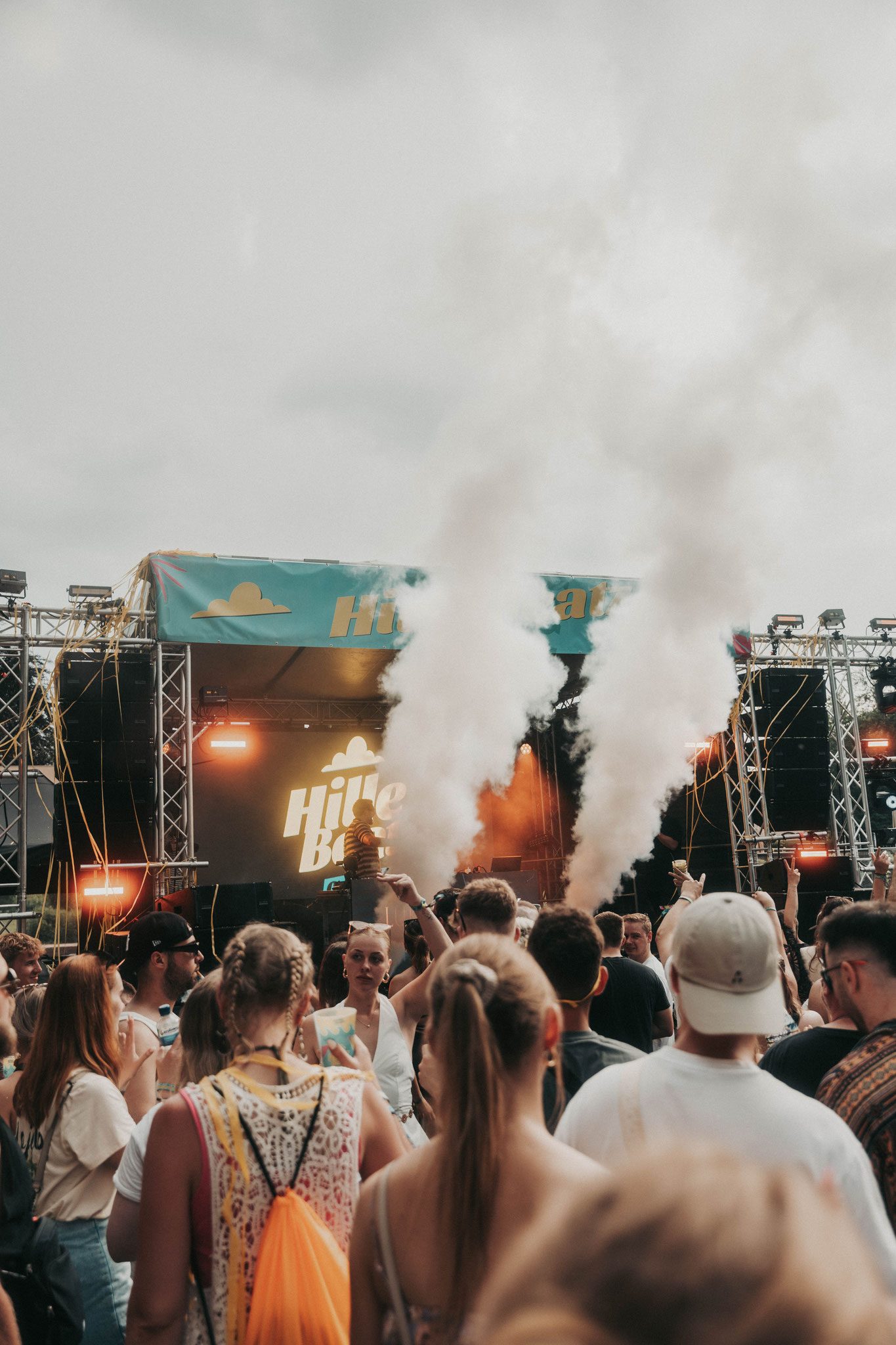 Outdoor Festival Bühne mit vielen Menschen und Nebel im Vordergrund.